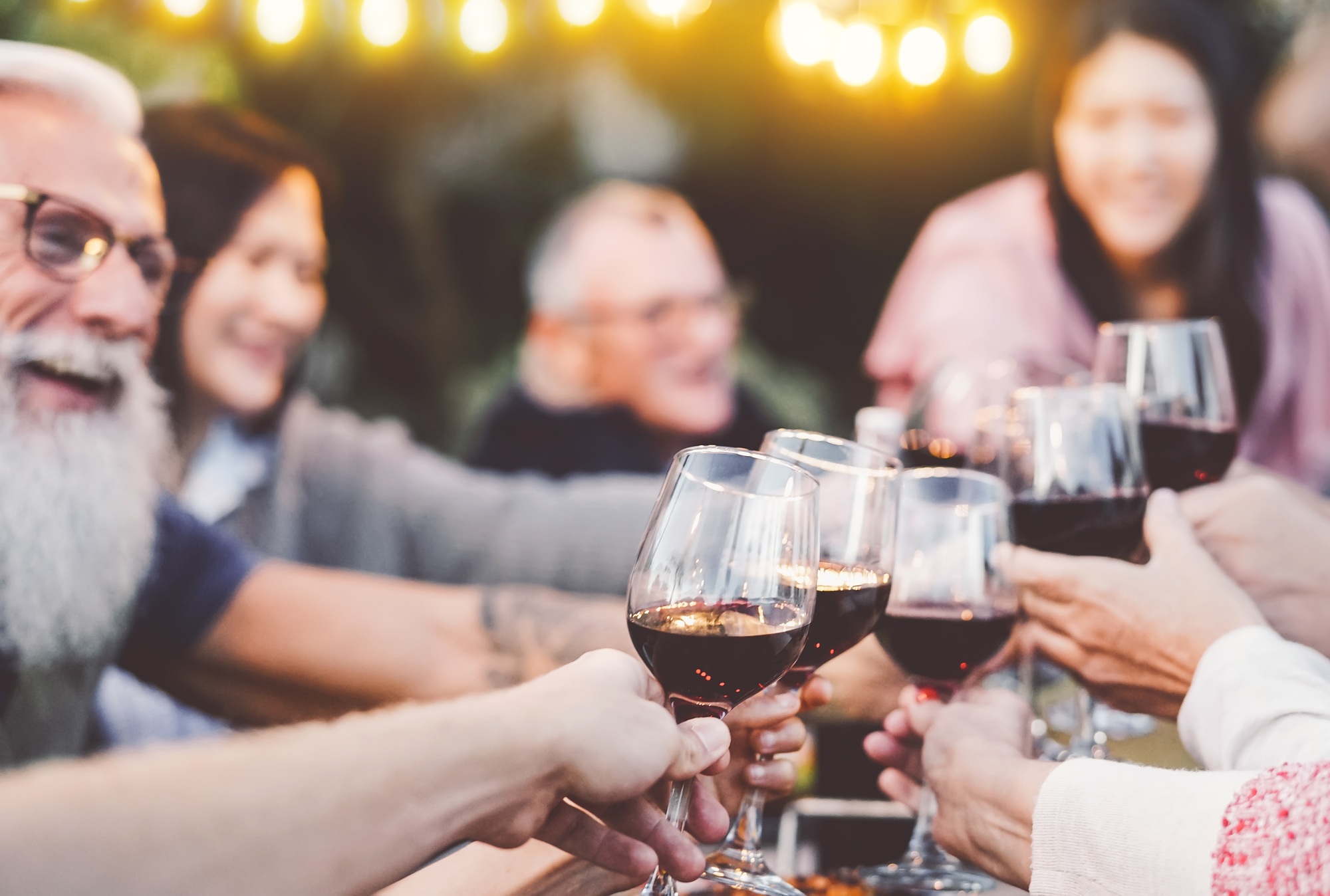 Happy family dining and toasting red wine glasses in barbecue dinner party